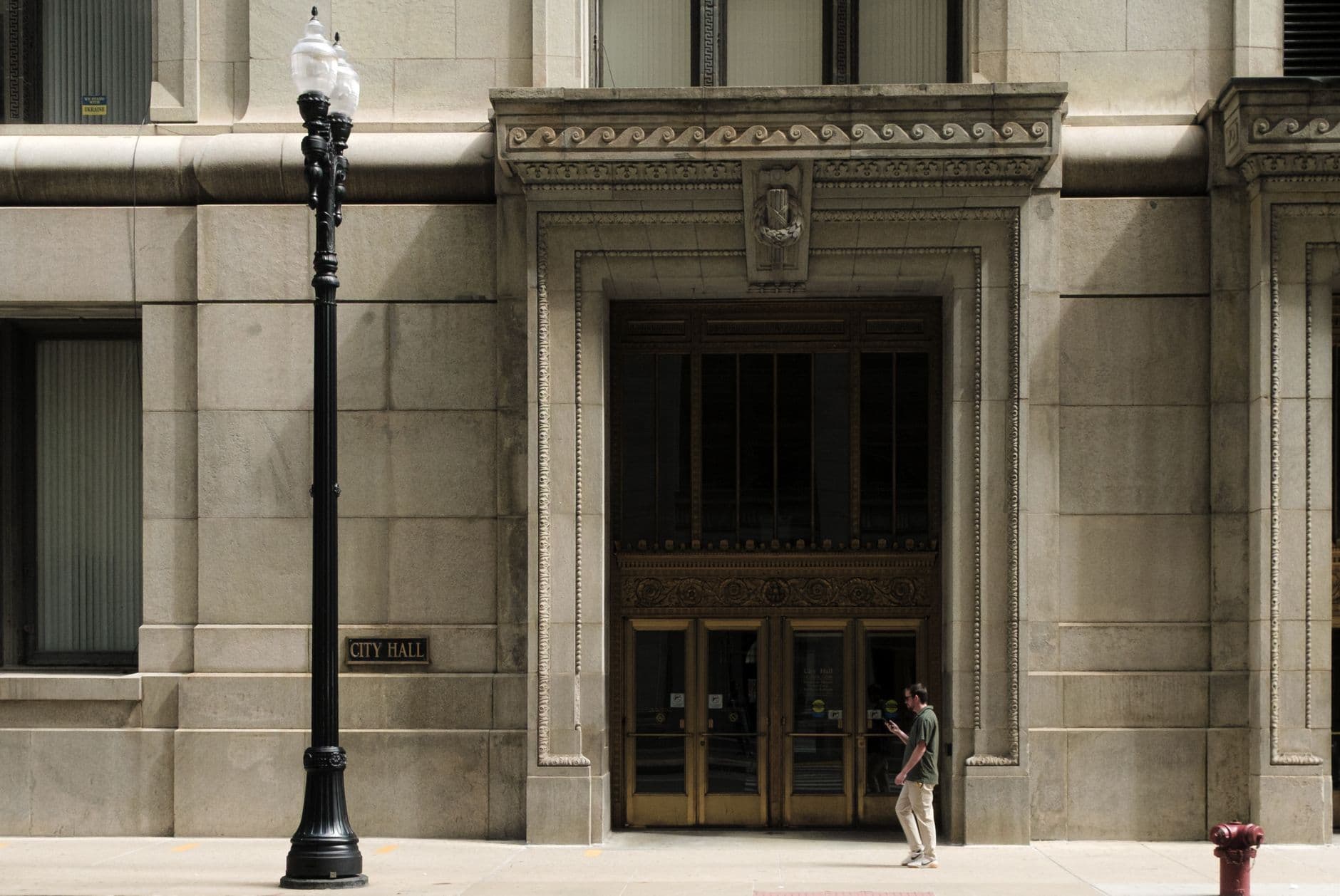 Exterior view of Chicago City Hall featuring intricate architecture and a lone pedestrian walking by.