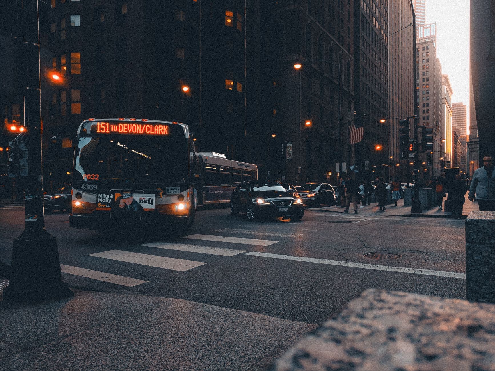 Urban scene with bus and traffic in a city setting at twilight, highlighting urban life.