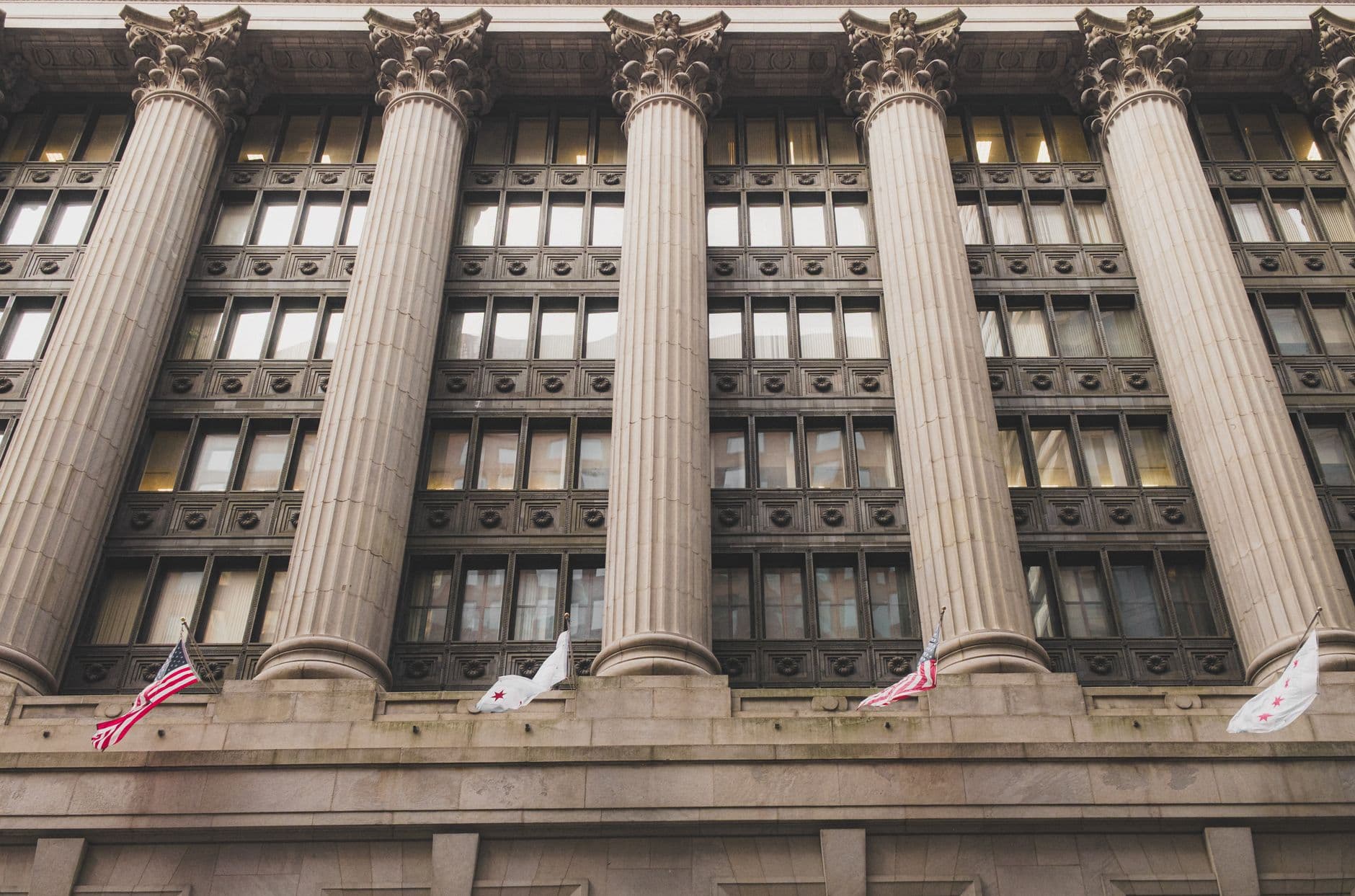 Elegant neoclassical facade with columns and flags in downtown Chicago.